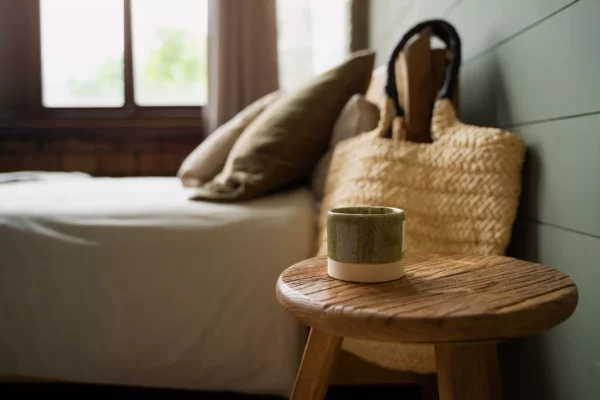 Chambre d'appartement boutique avec lit, coussins, table en bois et tasse dans la maison Talmühle au Schwarzwald