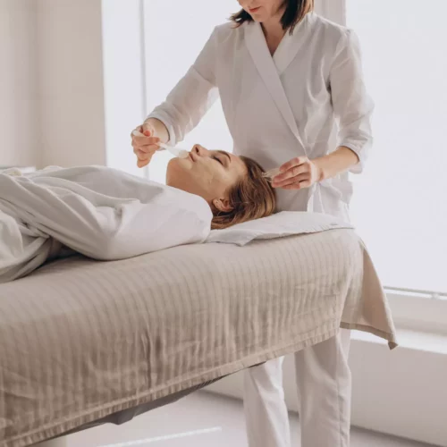 Beautician applying a face mask to a woman in the treatment room at the Maison Talmühle Black Forest boutique spa
