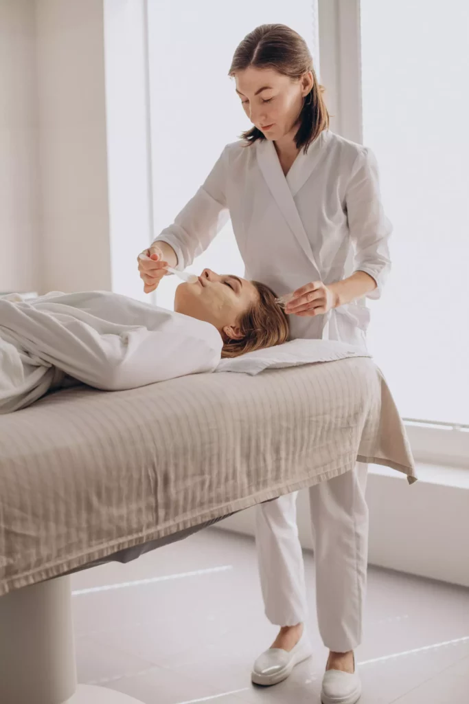 Beautician applying a face mask to a woman in the treatment room at the Maison Talmühle Black Forest boutique spa