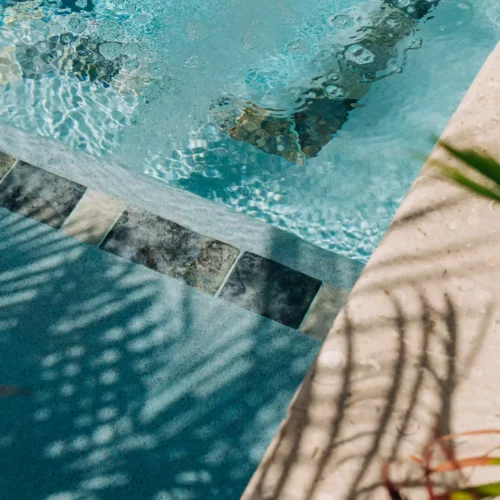 Close-up of a blue panoramic pool with bubbling water and plant shadows at the poolside at the boutique resort