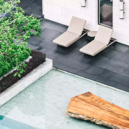 Modern panoramic pool with a wooden island, two loungers and plants at a Black Forest boutique resort spa