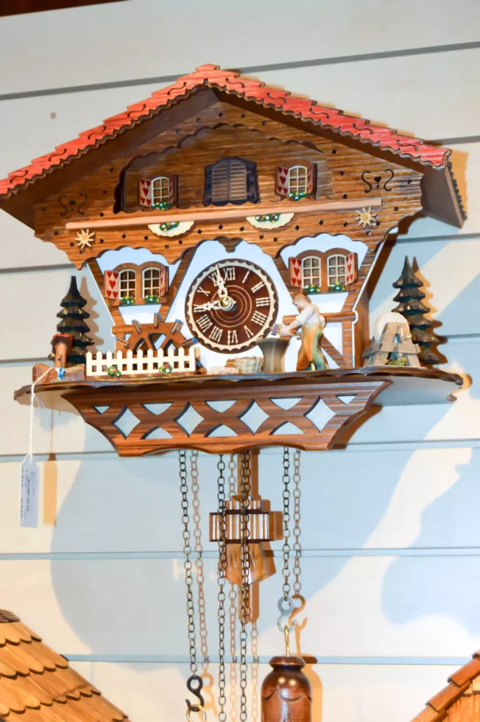 Traditional wooden Black Forest cuckoo clock with a carved house, figures and chains at Maison Talmühle boutique resort
