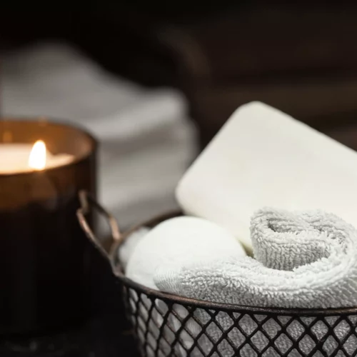 Wellness products with soap, bath salts and a towel in a wire basket beside a burning candle at the Black Forest boutique resort