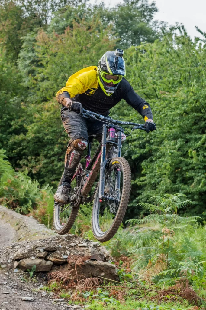 Mountain biker wearing a helmet and camera jumping over a rock on a forest trail in the Black Forest at Maison Talmühle Resort