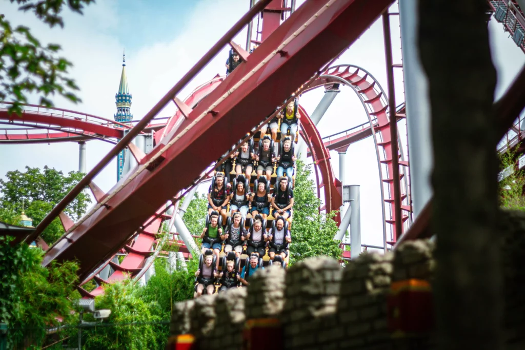 Rollercoaster carrying several passengers on the track in front of green forest and blue sky at the Europa-Park theme park