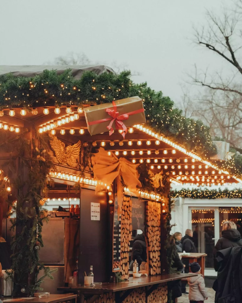 Festively decorated Christmas-market stall with fairy lights, fir greenery and gift decorations in winter at the Black Forest resort
